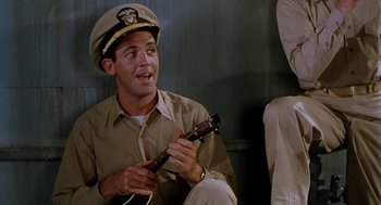 Movie still from “The Caine Mutiny” (1954), directed by Edward Dmytryk – A man wearing a hat and holding a ukulele; Medium shot, Low angle