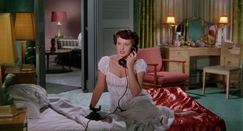 Movie still from “The Caine Mutiny” (1954), directed by Edward Dmytryk – A woman sitting on the ground talking on a phone; Medium shot, High angle