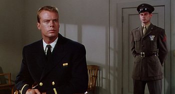 Movie still from “The Caine Mutiny” (1954), directed by Edward Dmytryk – A man in a suit and tie standing in front of a door; Medium shot, Over the shoulder angle
