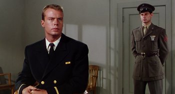 Movie still from “The Caine Mutiny” (1954), directed by Edward Dmytryk – A man in a suit and tie standing in front of a door; Medium shot, Low angle