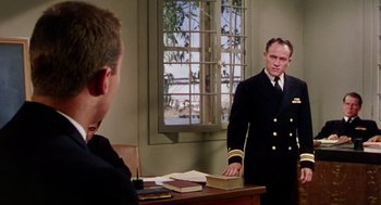 Movie still from “The Caine Mutiny” (1954), directed by Edward Dmytryk – A man in a uniform stands in front of a window; Medium shot, Over the shoulder angle