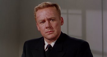 Movie still from “The Caine Mutiny” (1954), directed by Edward Dmytryk – A man wearing a suit and tie in front of a window; Close Up shot, Low angle