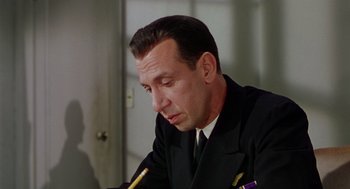 Movie still from “The Caine Mutiny” (1954), directed by Edward Dmytryk – A person wearing a suit writing on a paper; Close Up shot, Low angle