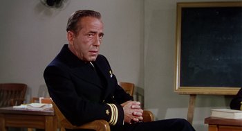Movie still from “The Caine Mutiny” (1954), directed by Edward Dmytryk – An older man wearing a uniform sitting in a chair; Medium shot, Over the shoulder angle