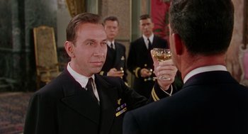 Movie still from “The Caine Mutiny” (1954), directed by Edward Dmytryk – A man in a navy uniform holding a glass of wine; Medium shot, Low angle