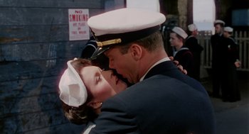 Movie still from “The Caine Mutiny” (1954), directed by Edward Dmytryk – A man and a woman in uniform kissing; Medium shot, Low angle