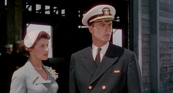 Movie still from “The Caine Mutiny” (1954), directed by Edward Dmytryk – A man and woman in formal wear standing next to each other in front of a building; Medium shot, Low angle