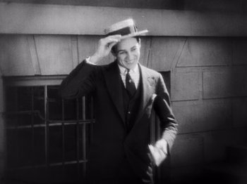 Movie still from “The Cameraman” (1928), directed by Buster Keaton – A black and white photo of a man wearing a suit and tie; Medium shot, High angle