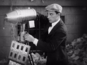 Movie still from “The Cameraman” (1928), directed by Buster Keaton – An old photo of a man using a light; Medium shot, Low angle