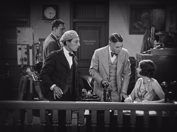 Movie still from “The Cameraman” (1928), directed by Buster Keaton – A group of men standing around a table; Medium shot, High angle