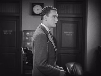 Movie still from “The Cameraman” (1928), directed by Buster Keaton – Black and white photograph of a man in a suit; Medium shot, High angle