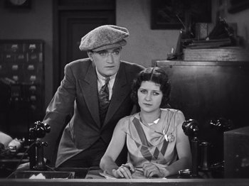 Movie still from “The Cameraman” (1928), directed by Buster Keaton – A man and a woman sitting at a desk; Medium shot, Low angle