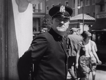 Movie still from “The Cameraman” (1928), directed by Buster Keaton – An old photo of a man in a police uniform; Medium shot, Low angle