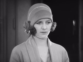 Movie still from “The Cameraman” (1928), directed by Buster Keaton – A woman wearing a cloche hat with a flower on it; Close Up shot, Low angle