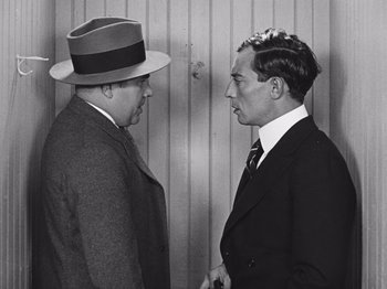 Movie still from “The Cameraman” (1928), directed by Buster Keaton – Two men in suits and hats facing one another; Medium shot, Over the shoulder angle