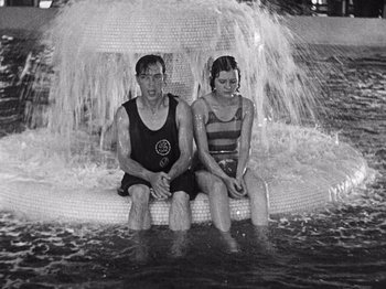 Movie still from “The Cameraman” (1928), directed by Buster Keaton – A man and a woman sitting on a raft in the water; Medium shot, High angle