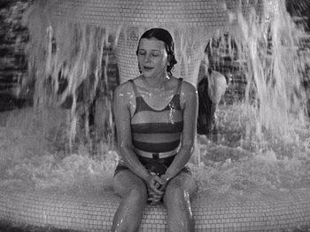 Movie still from “The Cameraman” (1928), directed by Buster Keaton – A woman sitting on a chair in front of a fountain; Medium shot, High angle