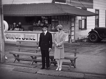 Movie still from “The Cameraman” (1928), directed by Buster Keaton – A man and a woman standing next to each other on a park bench; Wide shot, High angle