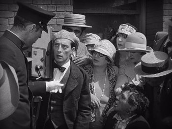 Movie still from “The Cameraman” (1928), directed by Buster Keaton – A group of people wearing hats and a man in a suit; Medium shot, High angle