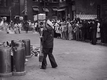 Movie still from “The Cameraman” (1928), directed by Buster Keaton – An old photo of a man walking down the street; Wide shot, High angle