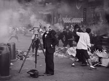 Movie still from “The Cameraman” (1928), directed by Buster Keaton – An old photo of a man standing in front of a camera; Wide shot, High angle