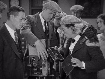 Movie still from “The Cameraman” (1928), directed by Buster Keaton – A group of men standing around each other; Medium shot, Low angle