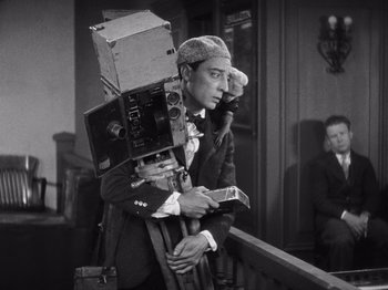Movie still from “The Cameraman” (1928), directed by Buster Keaton – An old photo of a man holding a camera; Medium shot, Low angle