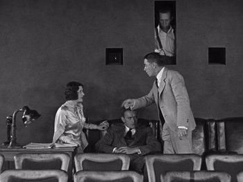 Movie still from “The Cameraman” (1928), directed by Buster Keaton – A man and a woman talking to another man in a suit; Wide shot, Over the shoulder angle