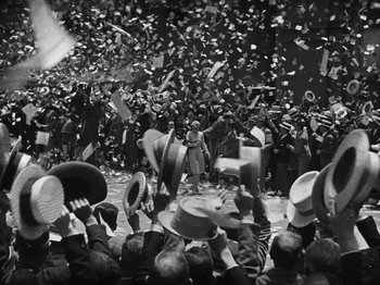 Movie still from “The Cameraman” (1928), directed by Buster Keaton – A crowd of people are gathered in the street to celebrate; Extreme Wide shot, High angle