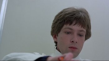 Movie still from “The Cassandra Crossing” (1976), directed by George P. Cosmatos – A young man is looking into the mirror while holding a pill; Close Up shot, Low angle