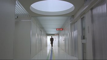 Movie still from “The Cassandra Crossing” (1976), directed by George P. Cosmatos – A man walking down a long hallway in a building; Extreme Wide shot, High angle