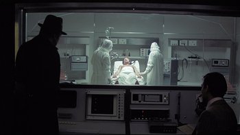 Movie still from “The Cassandra Crossing” (1976), directed by George P. Cosmatos – A man is in a hospital bed with two other men; Medium shot, High angle