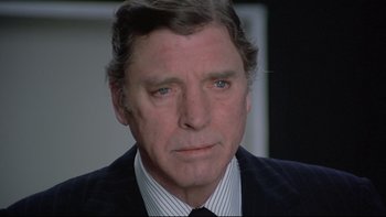 Movie still from “The Cassandra Crossing” (1976), directed by George P. Cosmatos – A person wearing a suit and tie; Close Up shot, Over the shoulder angle