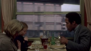 Movie still from “The Cassandra Crossing” (1976), directed by George P. Cosmatos – A man and a woman sitting at a dinner table; Medium shot, Over the shoulder angle