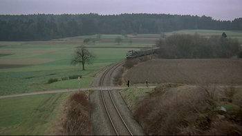 Movie still from “The Cassandra Crossing” (1976), directed by George P. Cosmatos – A train traveling down the train tracks near a field; Extreme Wide shot, High angle