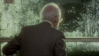 Movie still from “The Cassandra Crossing” (1976), directed by George P. Cosmatos – An older man in a suit looking out of a window; Medium shot, Over the shoulder angle