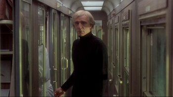 Movie still from “The Cassandra Crossing” (1976), directed by George P. Cosmatos – A man in a black shirt is walking down a hallway; Medium shot, Low angle