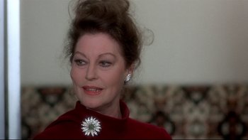 Movie still from “The Cassandra Crossing” (1976), directed by George P. Cosmatos – An older woman wearing a red dress and a flower brooch; Close Up shot, Over the shoulder angle