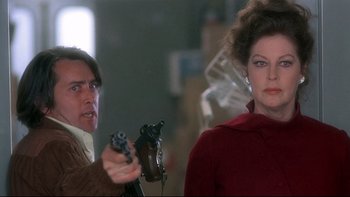 Movie still from “The Cassandra Crossing” (1976), directed by George P. Cosmatos – A man and a woman holding guns in a room; Close Up shot, Over the shoulder angle
