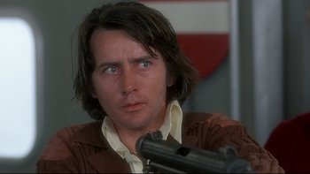 Movie still from “The Cassandra Crossing” (1976), directed by George P. Cosmatos – A person holding a gun; Close Up shot, Low angle