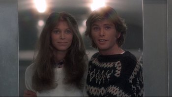 Movie still from “The Cassandra Crossing” (1976), directed by George P. Cosmatos – A man and a woman standing next to each other in front of lights; Medium shot, Low angle