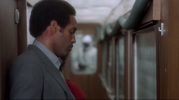 Movie still from “The Cassandra Crossing” (1976), directed by George P. Cosmatos – A man in a suit and tie looking out a window; Close Up shot, Over the shoulder angle