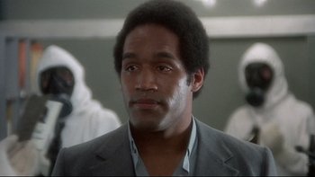 Movie still from “The Cassandra Crossing” (1976), directed by George P. Cosmatos – A man in a suit and tie in front of a group of people; Close Up shot, Low angle