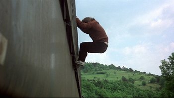 Movie still from “The Cassandra Crossing” (1976), directed by George P. Cosmatos – A man climbing a wall on top of a building; Wide shot, Low angle