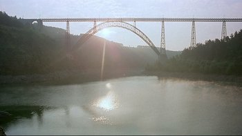 Movie still from “The Cassandra Crossing” (1976), directed by George P. Cosmatos – The sun is setting over a river and a bridge; Extreme Wide shot, Low angle