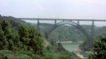 Movie still from “The Cassandra Crossing” (1976), directed by George P. Cosmatos – A large bridge over a river with trees in the background; Extreme Wide shot, Low angle