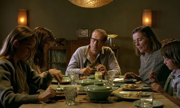 Movie still from “The Cement Garden” (1993), directed by Andrew Birkin – A group of people sitting at a table with plates; Medium shot, Over the shoulder angle
