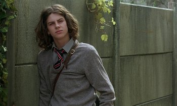 Movie still from “The Cement Garden” (1993), directed by Andrew Birkin – A man with long hair wearing a sweater and a tie; Medium shot, Low angle