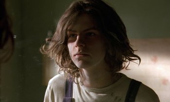Movie still from “The Cement Garden” (1993), directed by Andrew Birkin – A man with long hair is looking at the camera; Close Up shot, Low angle