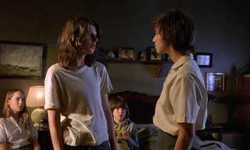 Movie still from “The Cement Garden” (1993), directed by Andrew Birkin – Two young women and a young boy in a room; Medium shot, Over the shoulder angle